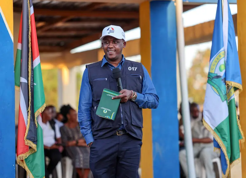 Governor Mutula Kilonzo Jr. addressing the Kitise community meeting, holding a green folder.