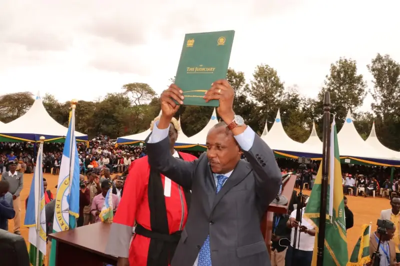 Mutula Kilonzo Jr. holding the Constitution above his head during his 2022 inauguration in Wote.